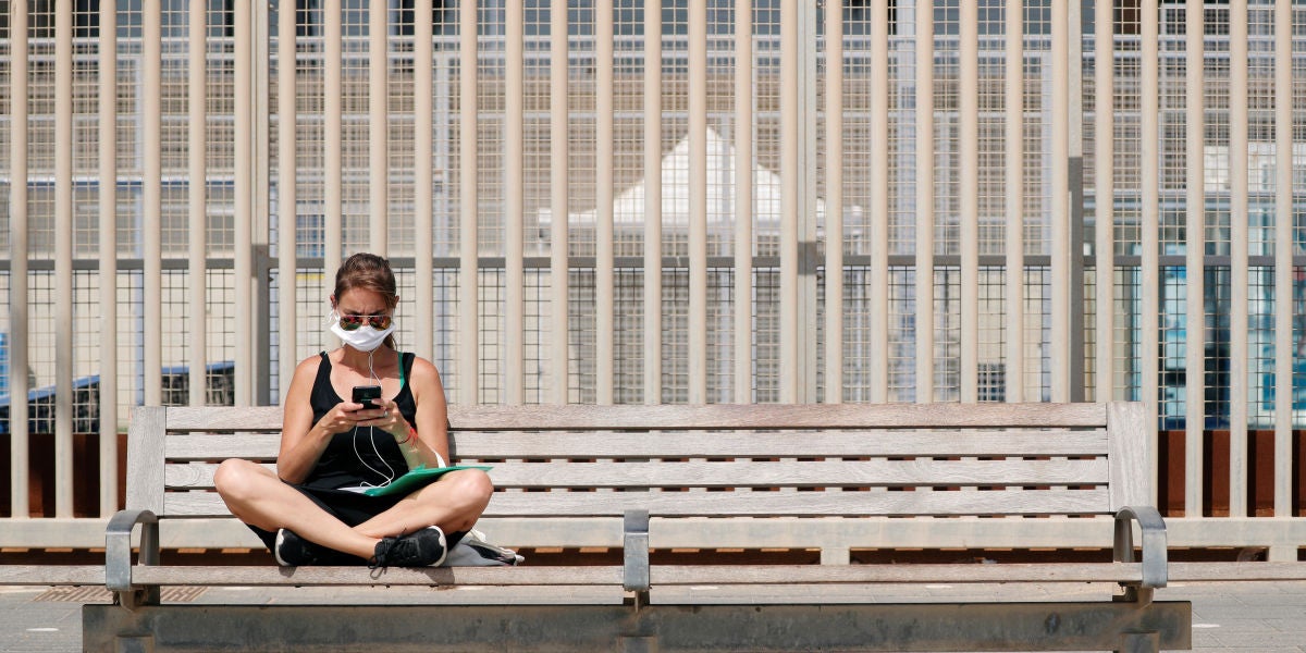 Una mujer con mascarilla, sentada en un banco de Barcelona