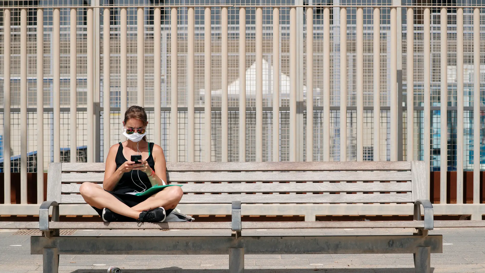 Una mujer con mascarilla, sentada en un banco de Barcelona