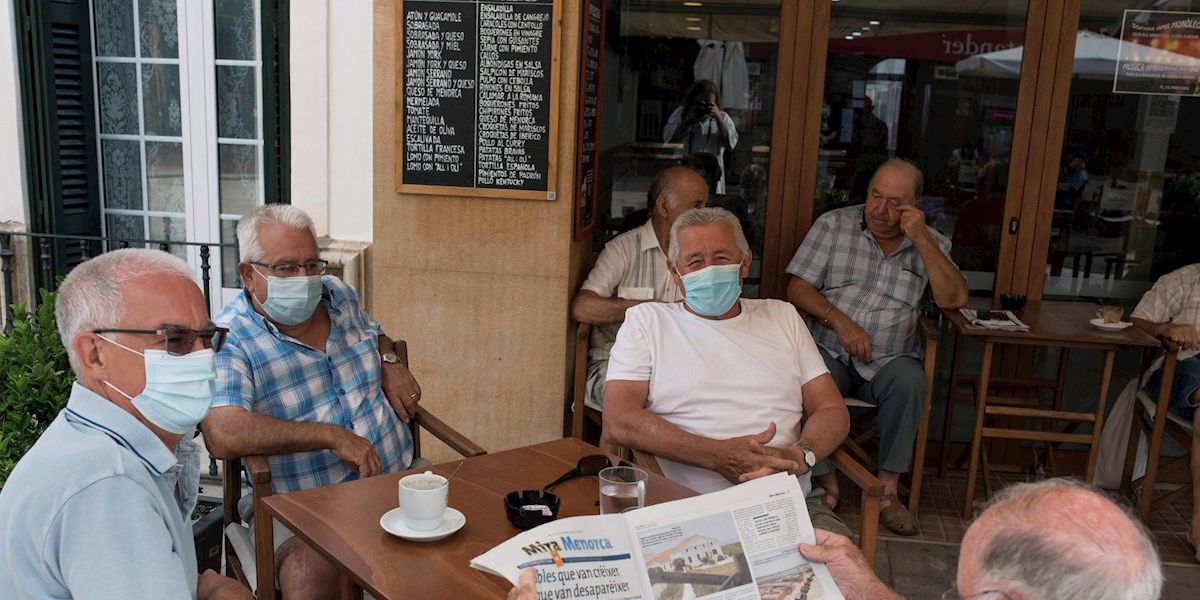 Un grupo de amigos tomando un café en un bar con la mascarilla puesta