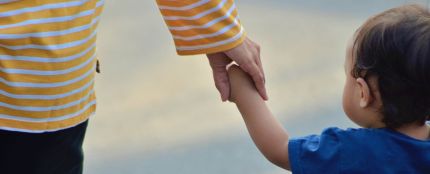 Un niño pequeño pasea de la mano de su madre.