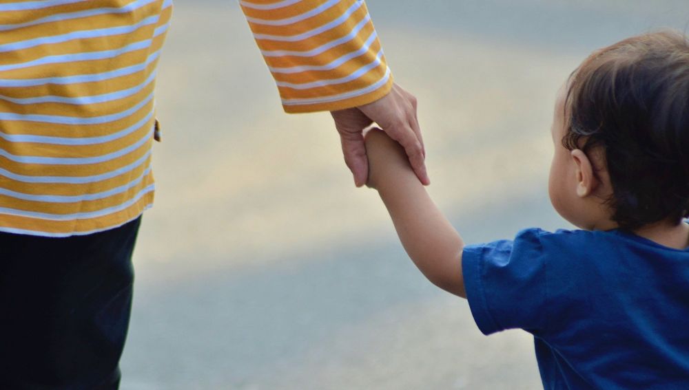 Un niño pequeño pasea de la mano de su madre.