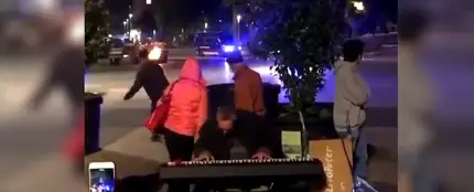 Un hombre toca con los disturbios de fondo en Barcelona Un hombre toca con los disturbios de fondo en Barcelona