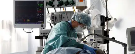 Una médico trata a un paciente de COVID-19 en una UCI. Una médico trata a un paciente de COVID-19 en una UCI.