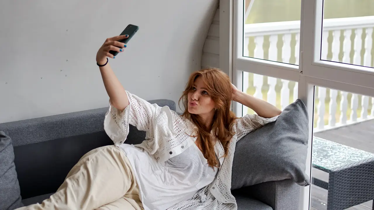 Una chica haciéndose un selfie en un sofá Una chica haciéndose un selfie en un sofá