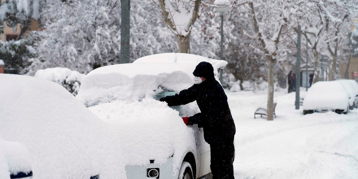 Un hombre quita la nieve de su coche