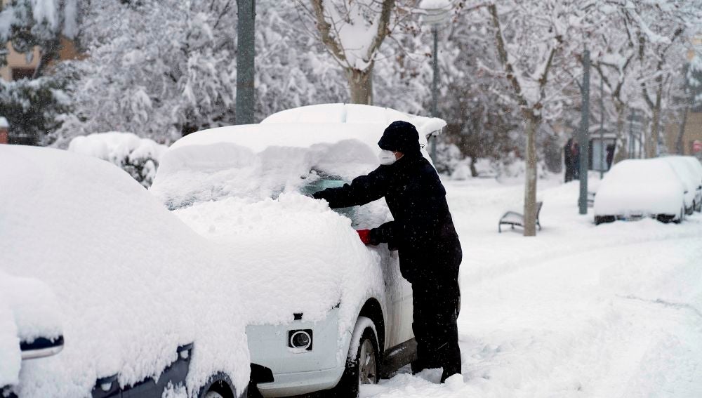 Un hombre quita la nieve de su coche