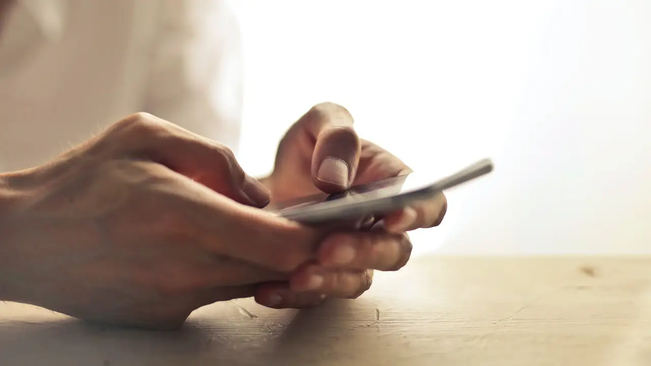 Una persona sostiene el teléfono móvil entre las manos Una persona sostiene el teléfono móvil entre las manos