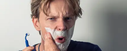 Joven afeitándose con maquinilla Joven afeitándose con maquinilla