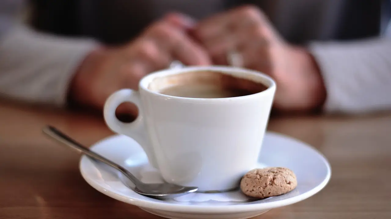 Un café, con una galleta y una cucharilla Un café, con una galleta y una cucharilla