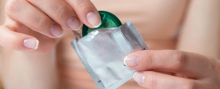 Mujer abriendo un preservativo Mujer abriendo un preservativo