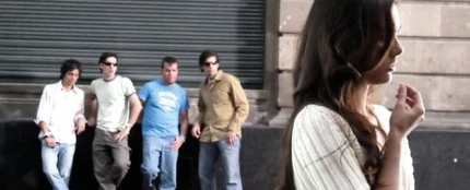 Un grupo de hombres observa a una mujer en la vía pública. Un grupo de hombres observa a una mujer en la vía pública.