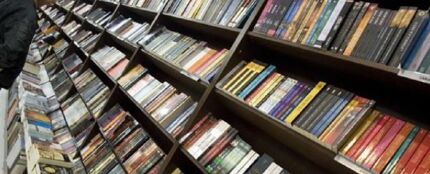 Un hombre ojea varios libros en una librería Un hombre ojea varios libros en una librería