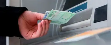 Un hombre saca euros de un cajero automático Un hombre saca euros de un cajero automático