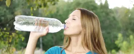 Una mujer bebiendo de una botella de plástico Una mujer bebiendo de una botella de plástico
