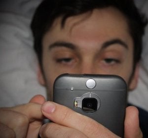 Hombre mirando el móvil en la cama Hombre mirando el móvil en la cama