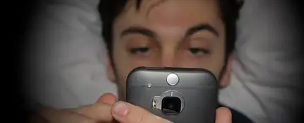 Hombre mirando el móvil en la cama Hombre mirando el móvil en la cama
