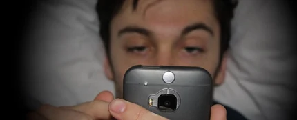 Hombre mirando el móvil en la cama Hombre mirando el móvil en la cama