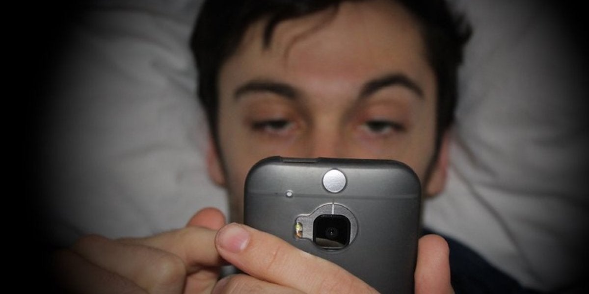 Hombre mirando el móvil en la cama