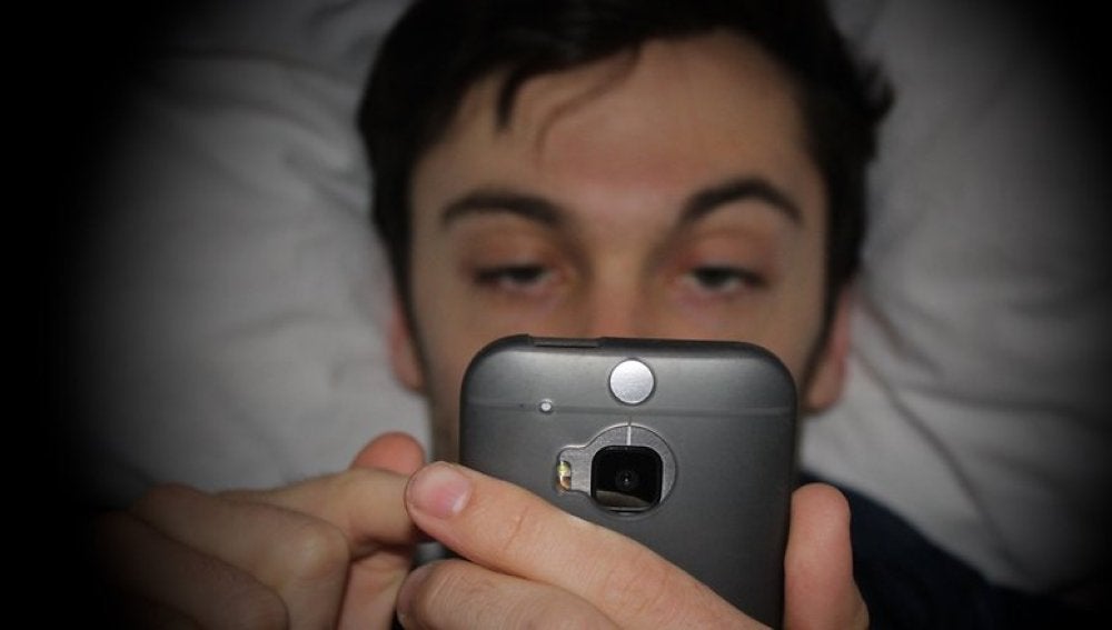Hombre mirando el móvil en la cama