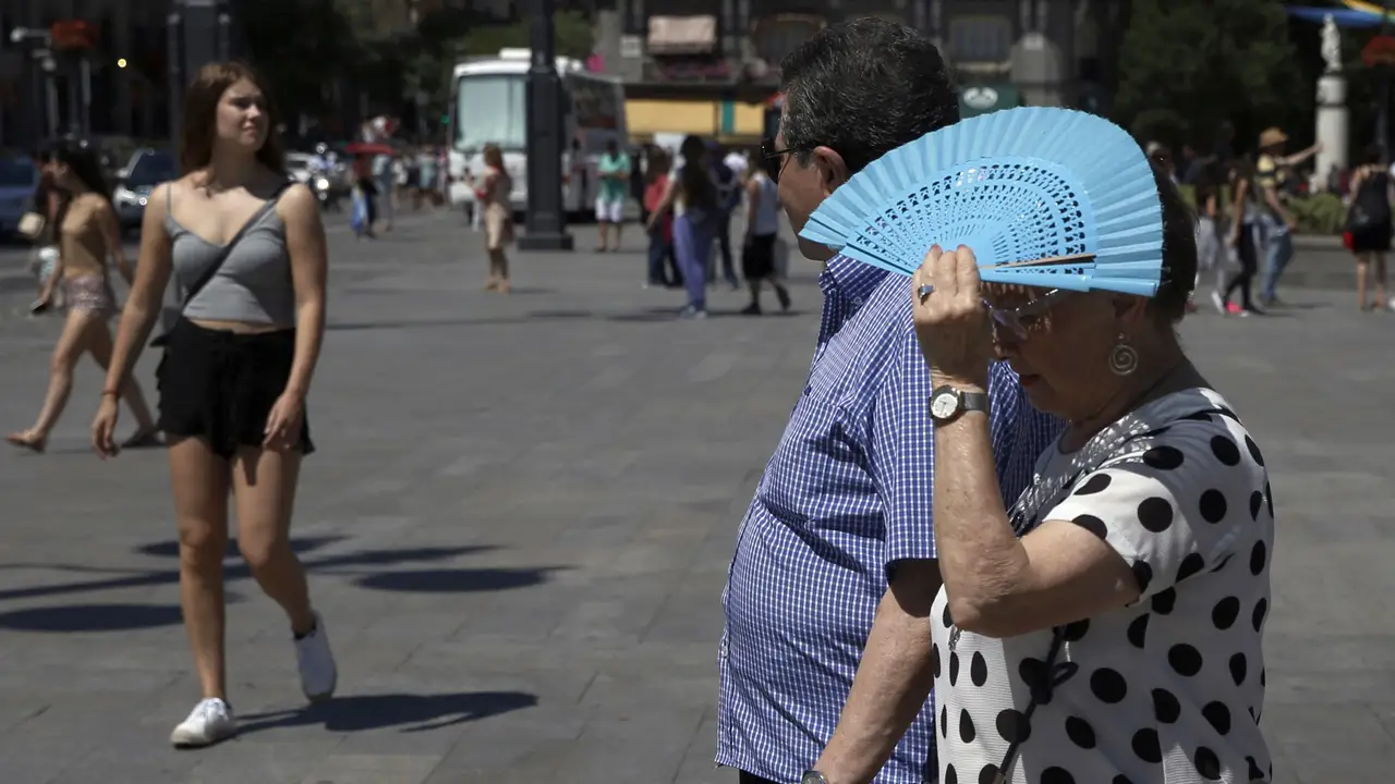 Imagen de archivo de una mujer tapándose con el abanico por el calor Imagen de archivo de una mujer tapándose con el abanico por el calor