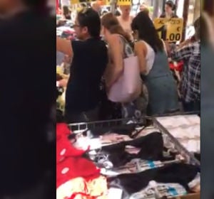 Una mujer robando la cartera a otra en un mercadillo Una mujer robando la cartera a otra en un mercadillo