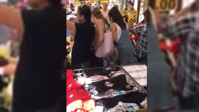 Una mujer robando la cartera a otra en un mercadillo