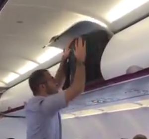 Un hombre intentando meter su maleta en un avión Un hombre intentando meter su maleta en un avión