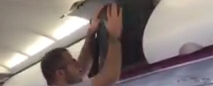 Un hombre intentando meter su maleta en un avión