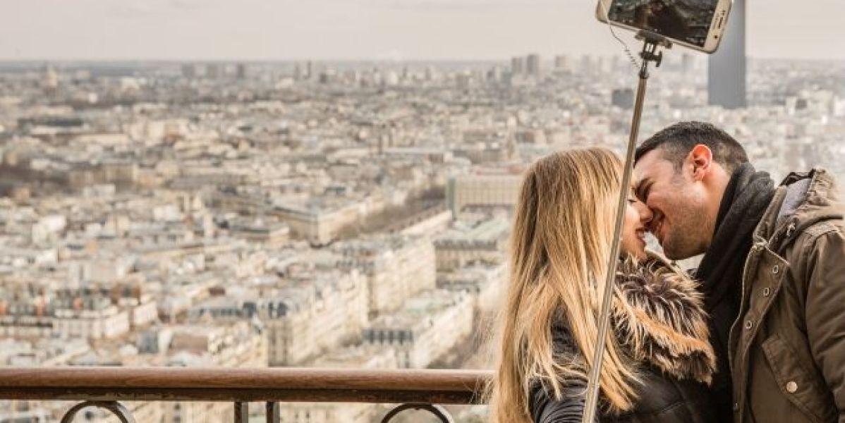 couple kissing while holding a selfie_643x397
