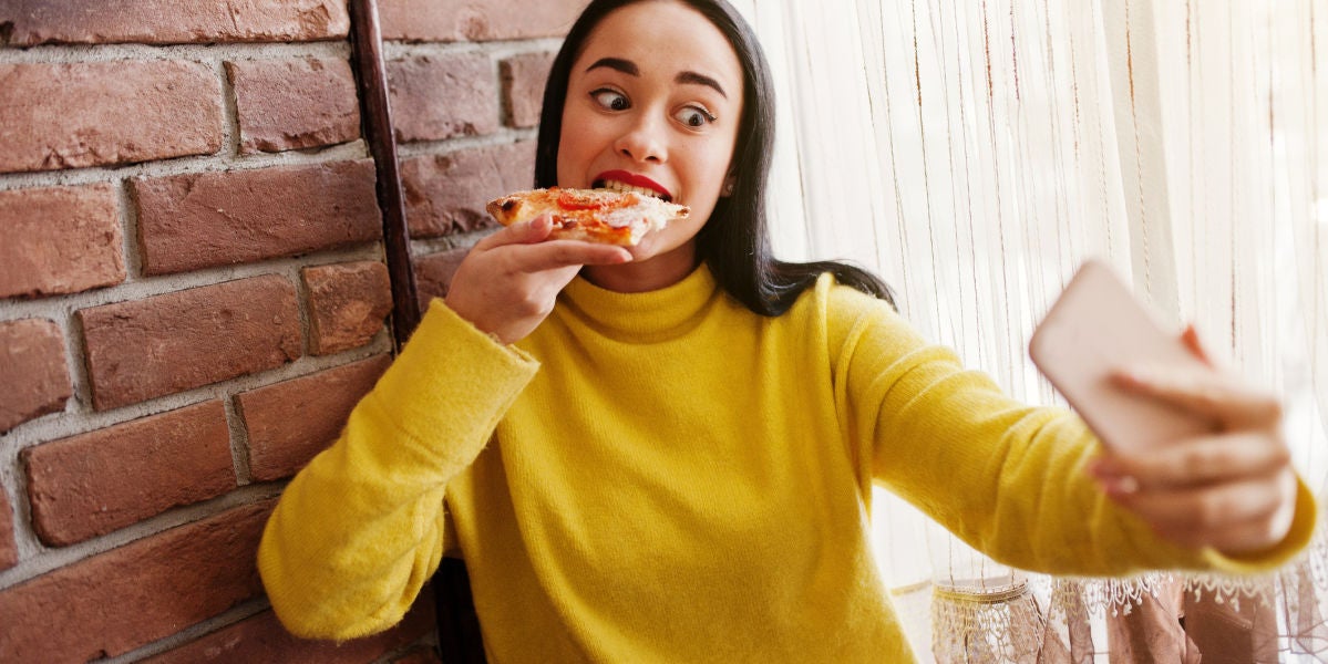 Chica grabándose en Instagram Stories mientras come una pizza