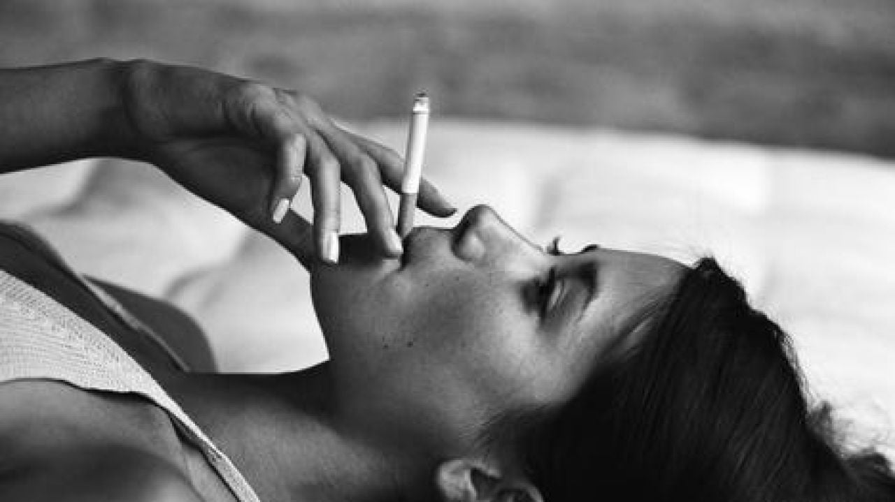 Chica fumando en la cama