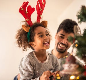 Niña emocionada decorando un árbol de Navidad Niña emocionada decorando un árbol de Navidad
