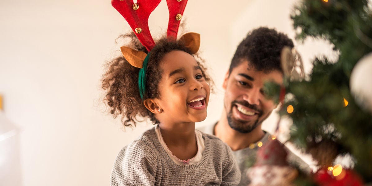 Niña emocionada decorando un árbol de Navidad