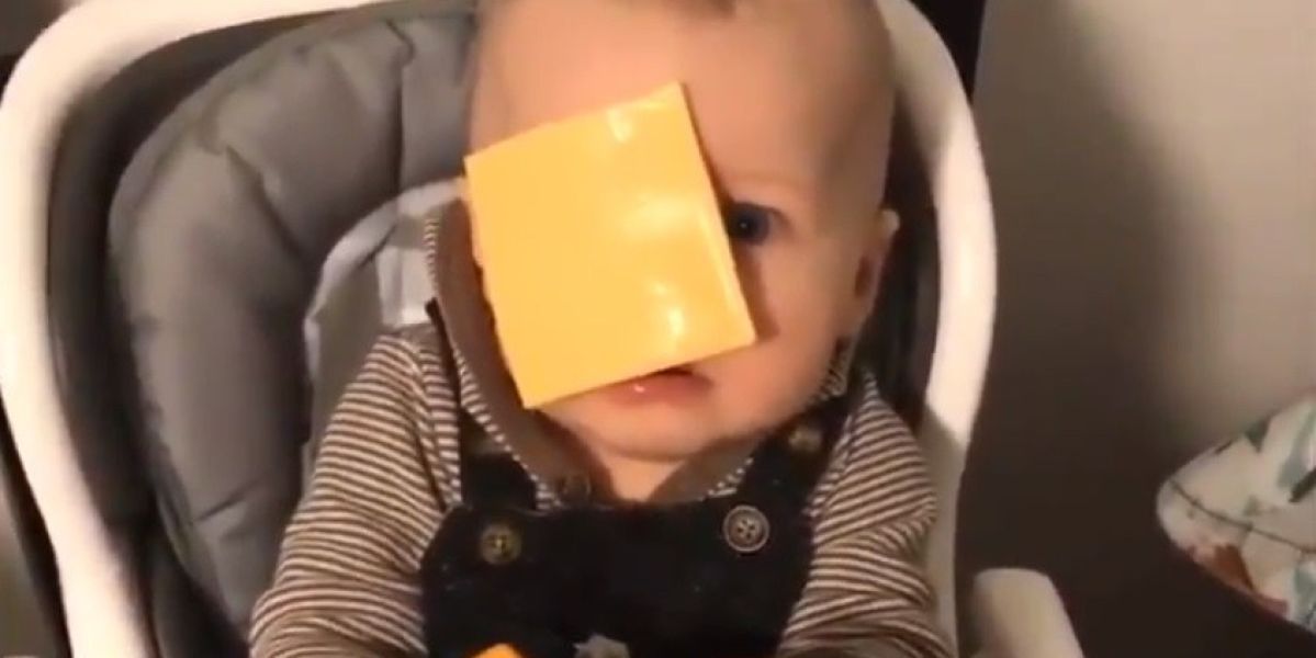 Un bebé con una loncha de queso en la cara.