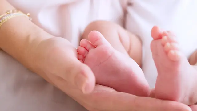 Una madre sosteniendo los pies de su bebé