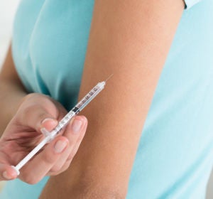 Una mujer aplicándose una inyección Una mujer aplicándose una inyección