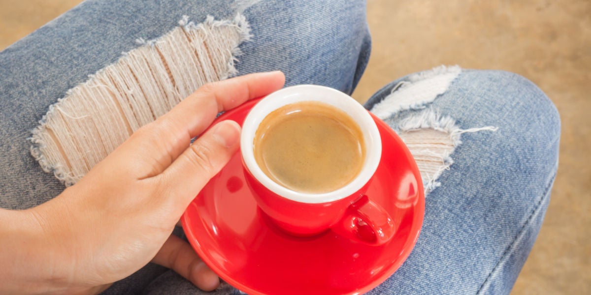 Chica con jeans tomándose un café
