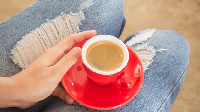 Chica con jeans tomándose un café