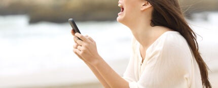 Joven enfadada que mira su teléfono móvil