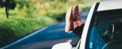 Una mujer sacando los pies por la ventanilla del coche Una mujer sacando los pies por la ventanilla del coche