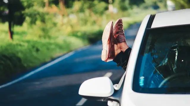 Una mujer sacando los pies por la ventanilla del coche