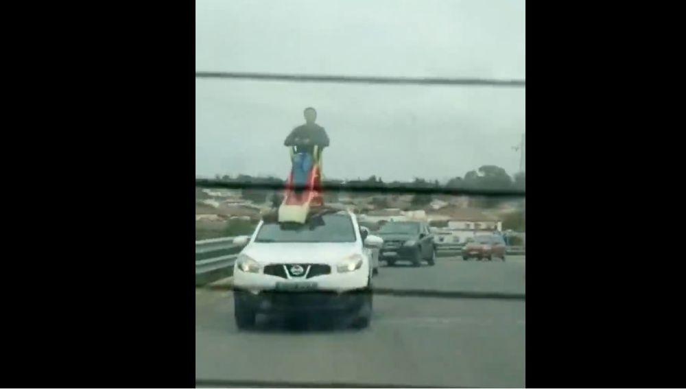 Un hombre subido a un tobogán en el techo de un coche en Chiclana