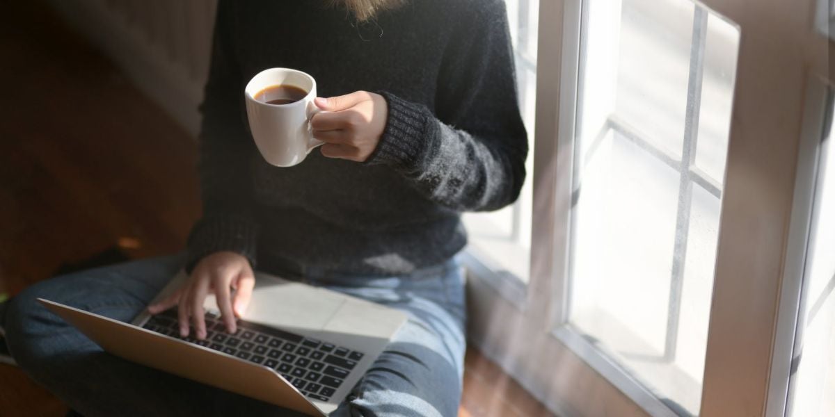 Una mujer bebiendo café y usando el portátil
