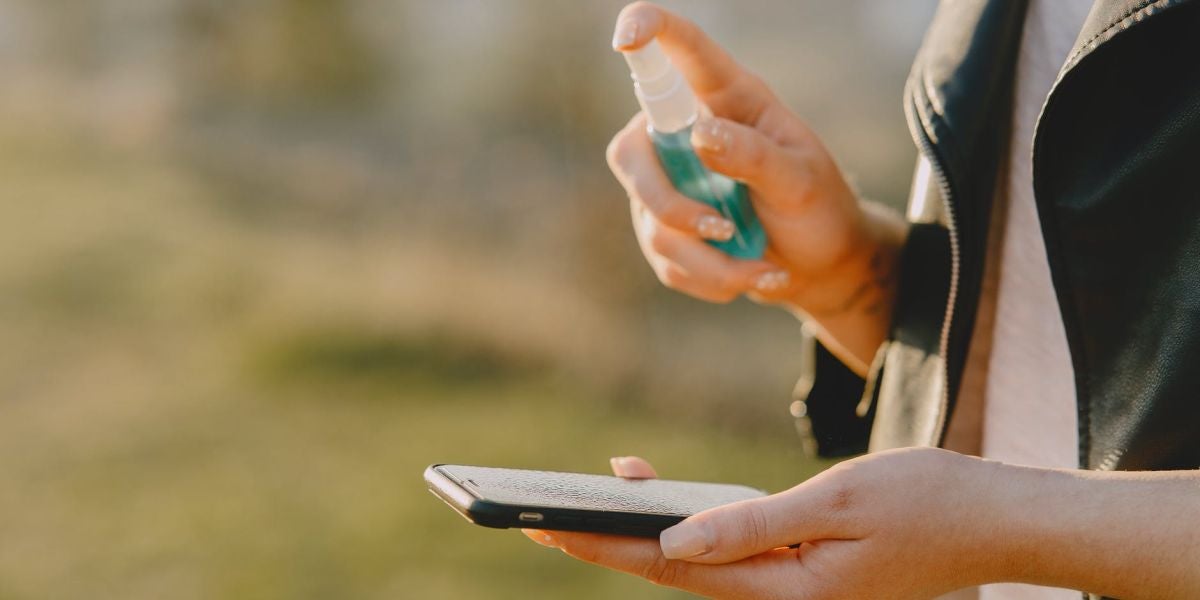 Una mujer desinfectando su teléfono móvil