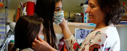 Una mujer prueba mascarillas a dos niñas Una mujer prueba mascarillas a dos niñas