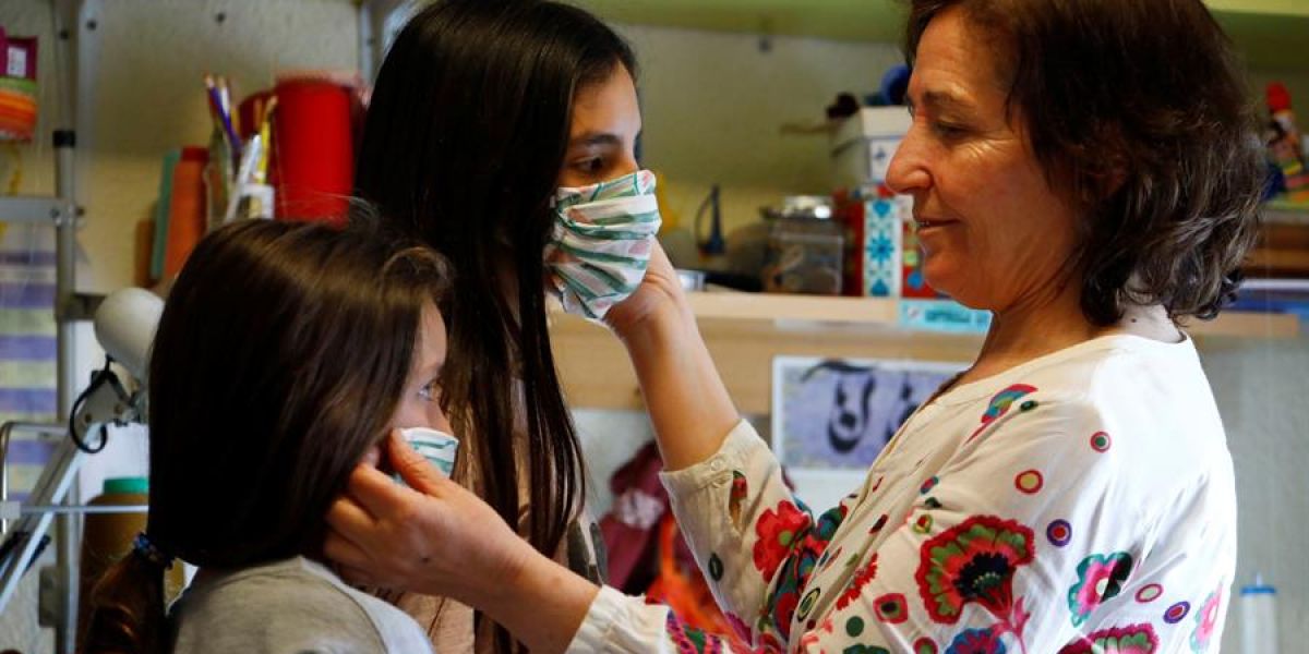 Una mujer prueba mascarillas a dos niñas