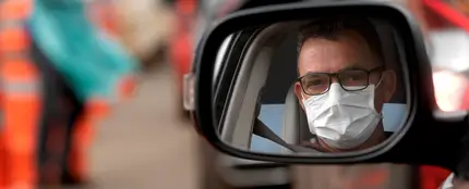 Un hombre con mascarilla en su coche Un hombre con mascarilla en su coche