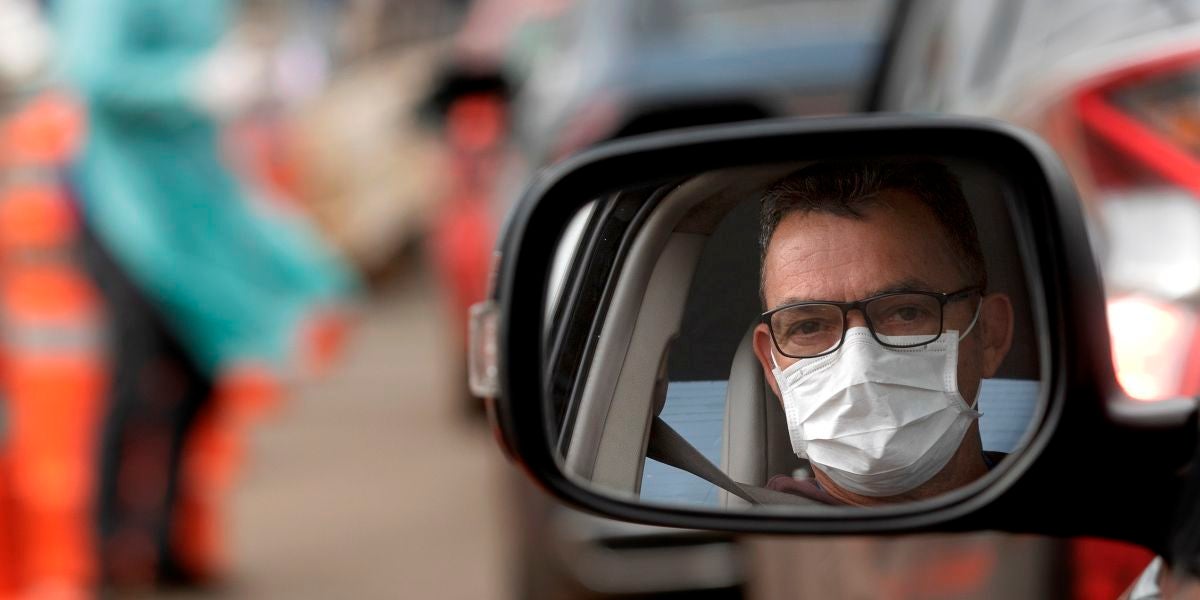Un hombre con mascarilla en su coche