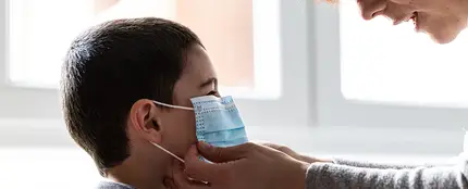 Una mujer coloca una mascarilla a un niño Una mujer coloca una mascarilla a un niño