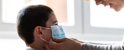 Una mujer coloca una mascarilla a un niño Una mujer coloca una mascarilla a un niño